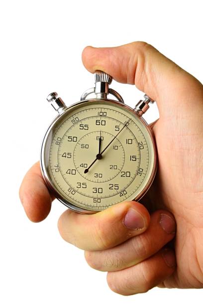 istock Older mechanical wind up stop watch held in left hand with fingers on reset positions, white background 882041572