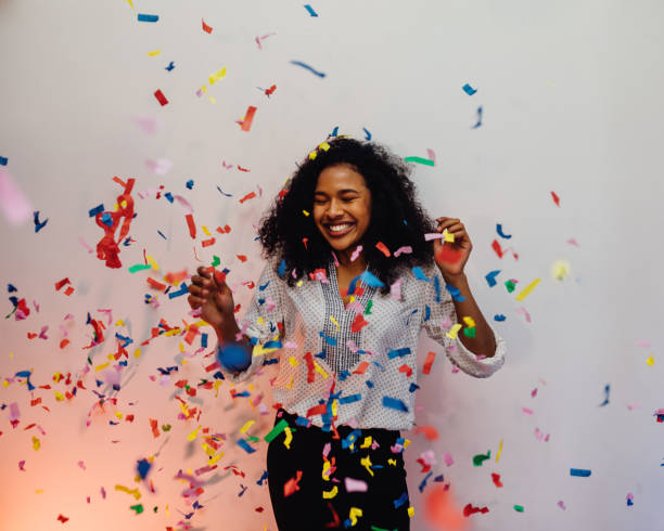 istock Happy woman under confetti, standing indoors with her eyes closed 882096464