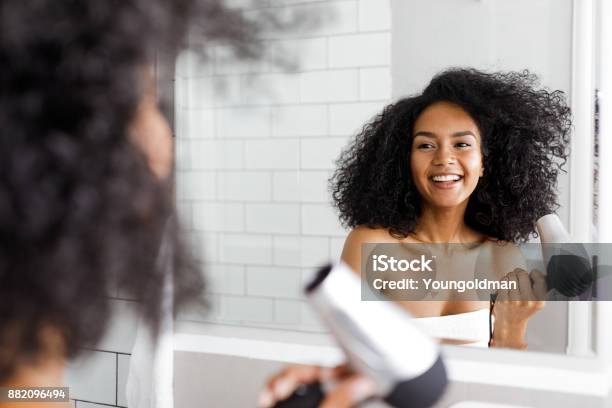 Smiling Woman With Hair Dryer Looking At Mirror Stock Photo - Download Image Now - Hair Dryer, Curly Hair, Blow Drying Hair