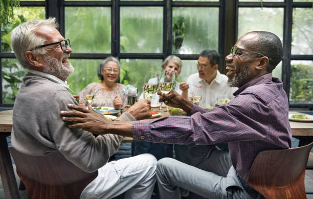 mature friends at a dinner party - retirement living imagens e fotografias de stock