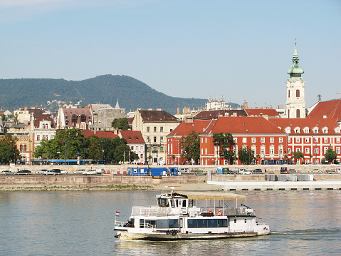 Budapest: The ship sails along the Danube River on the background of the Buda waterfront.