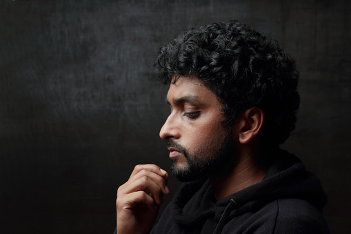 Portrait of a gloomy young man in a dark background