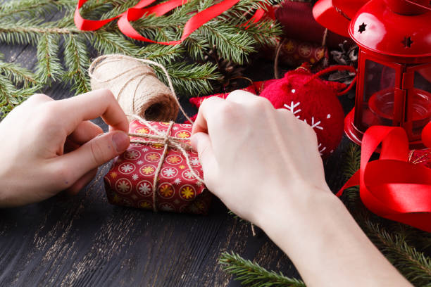 istock hands are wrapping a christmas gift on wooden background 882122208