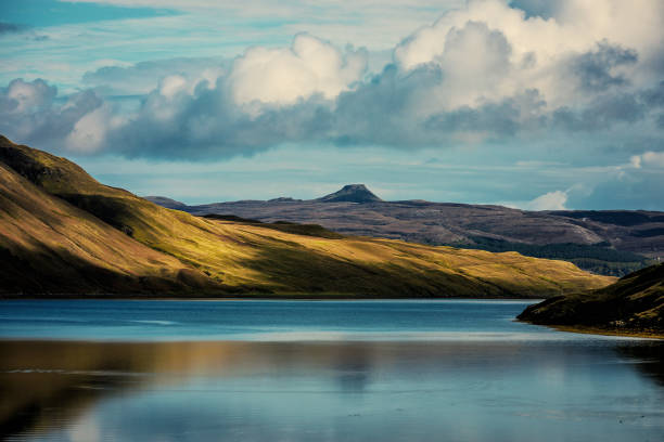 lago blu scozzese che riflette le montagne verdi - loch assynt foto e immagini stock