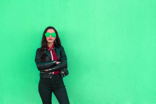 portrait of confident young woman with colorful glasses on green background - funky contemporary casual sex symbol imagens e fotografias de stock