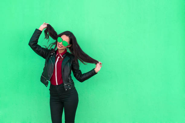 mulher jovem, brincando com o cabelo dela sobre fundo verde - funky contemporary casual sex symbol - fotografias e filmes do acervo