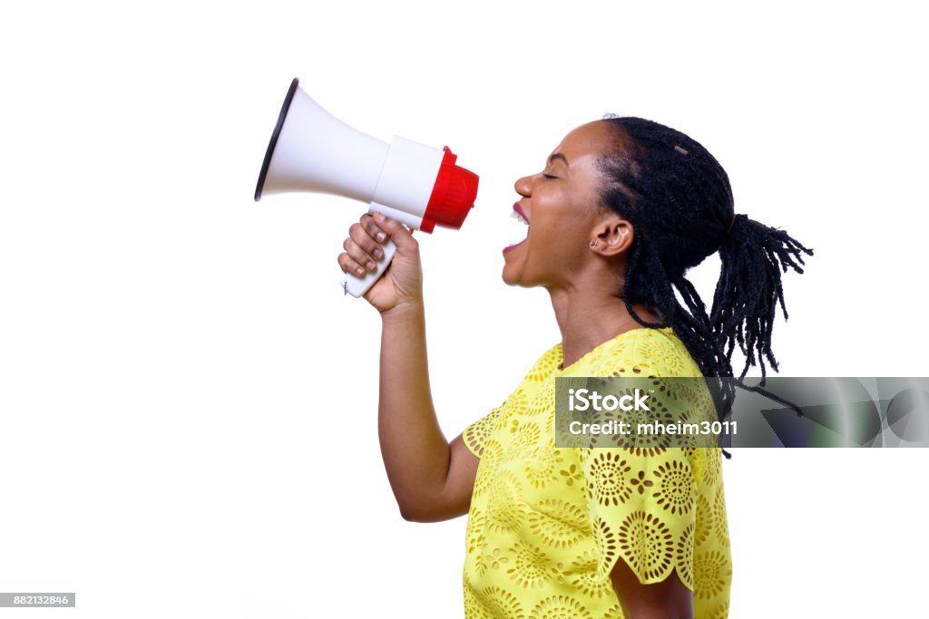 African American woman shouting at megaphone Profile view of African American woman shouting at megaphone while standing against white background Megaphone Stock Photo