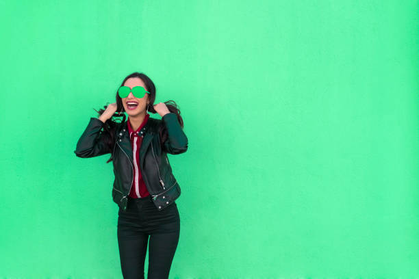 young woman laughing and pulling her hair on green background - funky contemporary casual sex symbol imagens e fotografias de stock