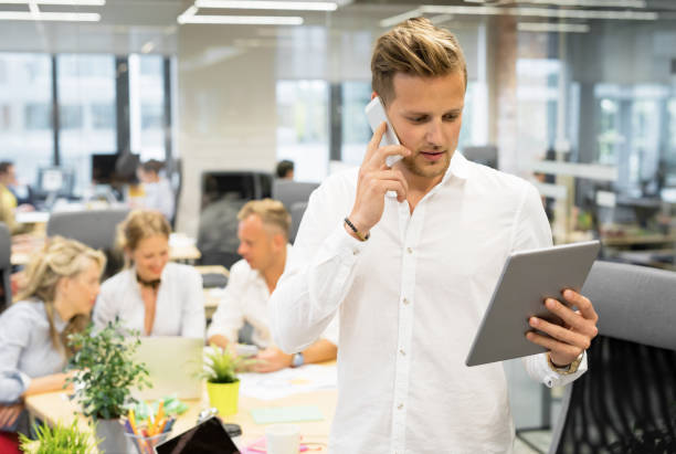 istock Man in open office talking on the phone and looking at tablet 882193574