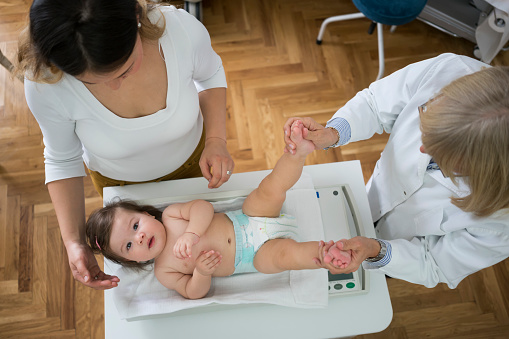 Woman with baby in doctor's office, baby scales