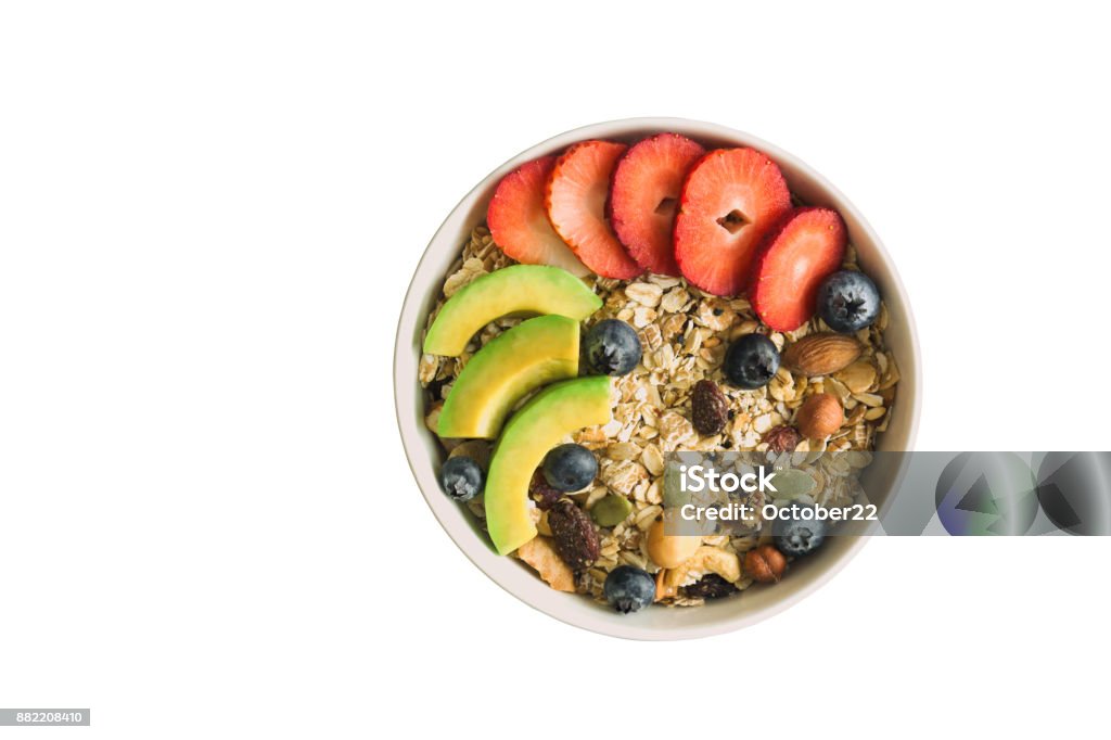 White isolated background with clipping paths muesli or granola on white bowl top with fresh blueberries, strawberries and avocado for breakfast in top view flat lay. Healthy food concept. White Background Stock Photo