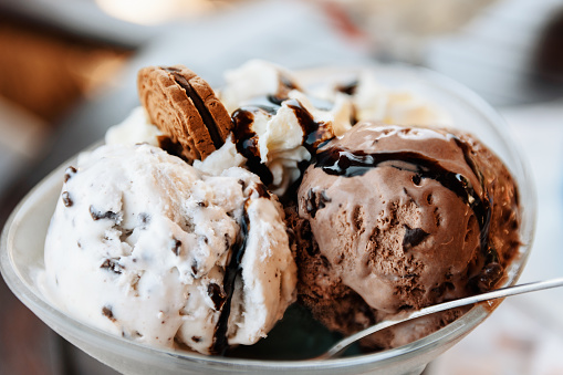 A close-up shot of a delicious ice cream sundae prepared with chocolate and vanilla ice cream, fresh whipped cream, chocolate sauce and a tasty cookie.