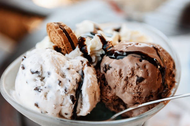 Ice Cream Sundae With Chocolate Sauce And Cookie A close-up shot of a delicious ice cream sundae prepared with chocolate and vanilla ice cream, fresh whipped cream, chocolate sauce and a tasty cookie. scoop shape photos stock pictures, royalty-free photos & images