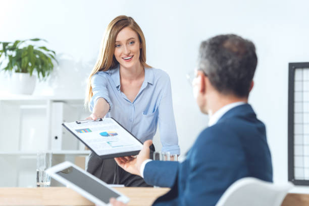 istock businesswoman passing clipboard with documents to partner 882222218
