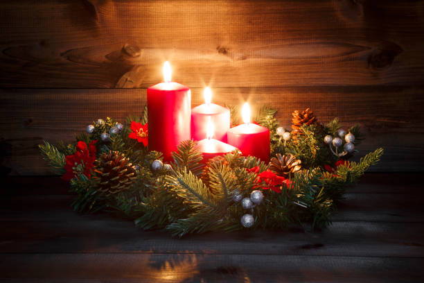 vierten advent - dekorierten adventskranz mit vier rote brennende kerzen auf einem hölzernen hintergrund mit festlichen atmosphäre - adventskranz stock-fotos und bilder