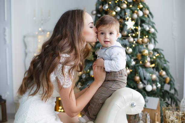 maman avec un petit fils près d’un bel arbre de noël dans sa maison - family cheerful family with one child texas photos et images de collection