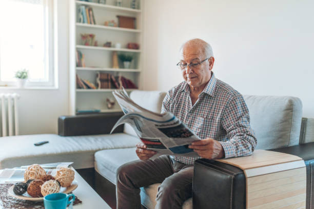 上級家庭で新聞を読む - senior adult relaxation sofa reading ストックフォトと画像