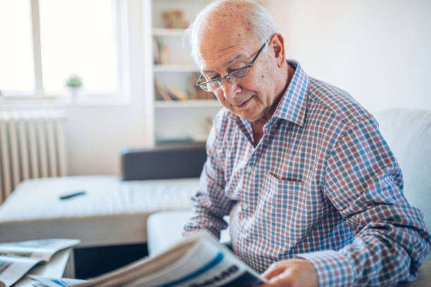 istock Senior at home reading newspaper 882250316