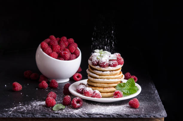 istock Bowl and  Pancakes with raspberries around on black backgound 882256028