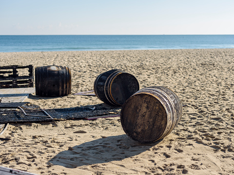 three burned wooden barrel on a beach