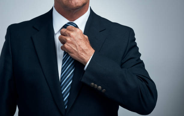 Adjust what you need to Studio shot of an unrecognizable businessman adjusting his tie against a grey  background man adjusting tie stock pictures, royalty-free photos & images