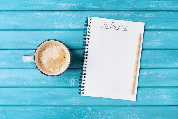 istock Cup of coffee and notepad with to do list on turquoise wooden table top view. Planning work concept. 882262054