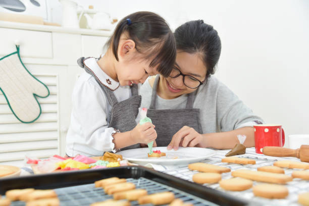 istock Asian Kid and young mother decorating cookies. 882262300