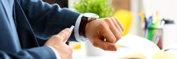 istock Man in suit and tie check out time at silver wristwatch 882267480