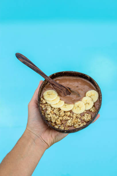istock Holding banana chocolate mouse in coconut bowl by the pool 882272748