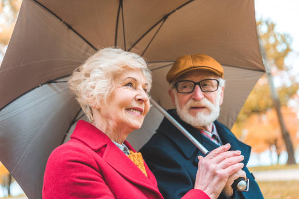 senior couple with umbrella - umbrella senior adult couple autumn imagens e fotografias de stock