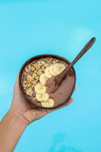 istock Holding banana chocolate mouse in coconut bowl by the pool 882272926