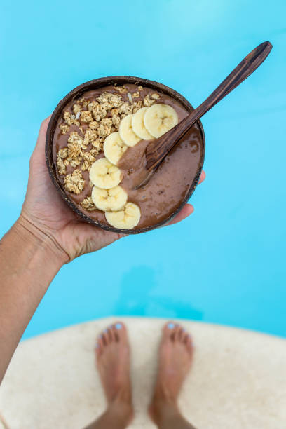 istock Holding banana chocolate mouse in coconut bowl by the pool 882273144