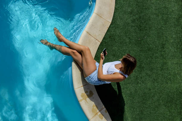 istock Woman using mobile phone by the pool 882284172