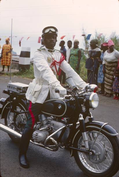Yaoundé, Kemerun, 1967. Motorized police escort of the then President of Cameroon on a BMW Motorcycle.In the background onlookers on the roadside.