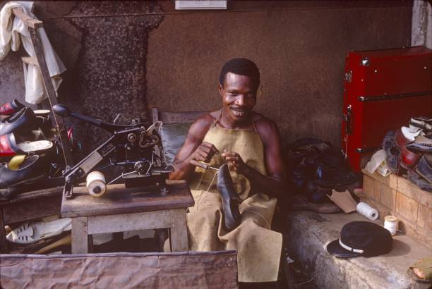 Yaoundé, Cameroon, 1967. Shoe repairman while working in his workshop.In Africa, recycling or repairing raw materials is one of the main industries for skilled craftsmen.