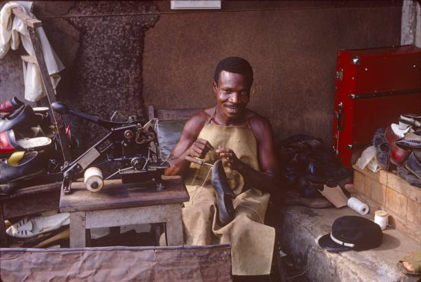 Shoe repairman, Cameroon Yaoundé, Cameroon, 1967. Shoe repairman while working in his workshop.In Africa, recycling or repairing raw materials is one of the main industries for skilled craftsmen. cameroon photos stock pictures, royalty-free photos & images