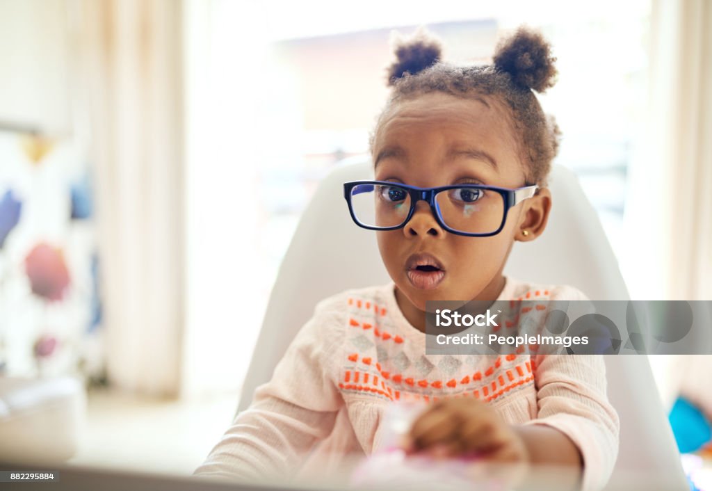 Oops... Cropped portrait of an adorable little girl looking shocked while sitting down at home Child Stock Photo