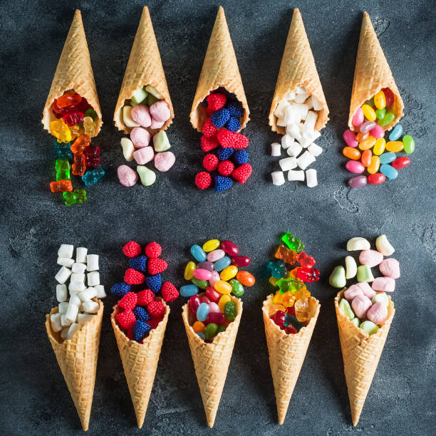 istock Colorful bright assorted candy in waffle cones on dark background. Flat lay. 882296048