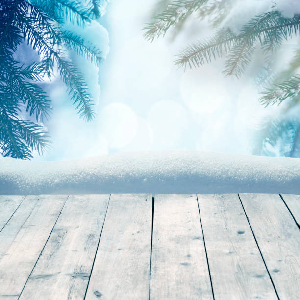 istock Winter background with snow-covered pine trees behind empty wooden planks 882299512