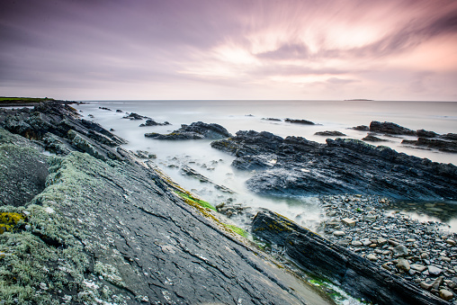 County Clare shore in Republic of Ireland. Long rocks at sunset in long exposure technique