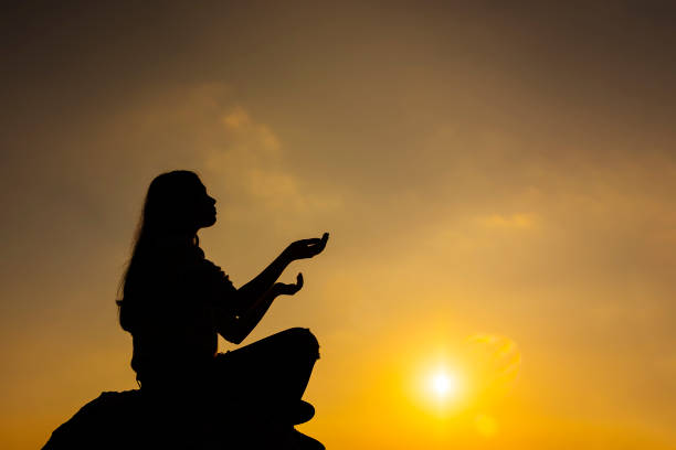 istock Prayer. Silhouette girl prays at sunset. 882306334