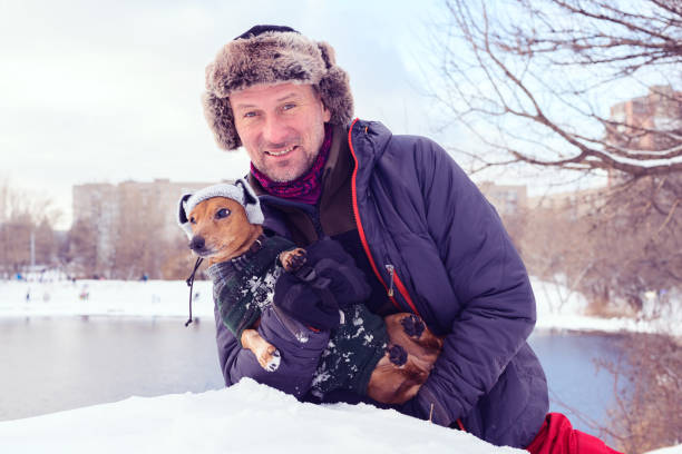 istock Smiling bearded man and small dog in funny winter hats 882311032