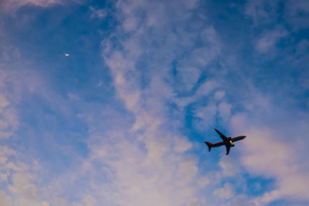 istock Flying airplane in blue sky with moon (silhouette ) 882314768