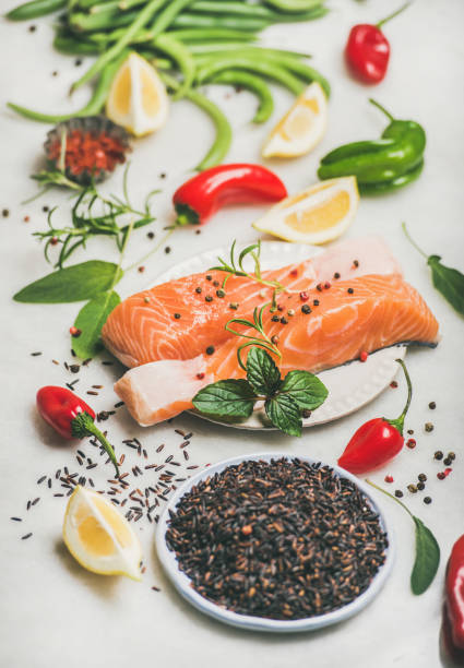 Raw salmon steaks with vegetables, greens and rice, marble background