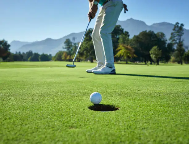 Low angle shot of a unrecognizable man hitting a golfball into a hole on a golf course