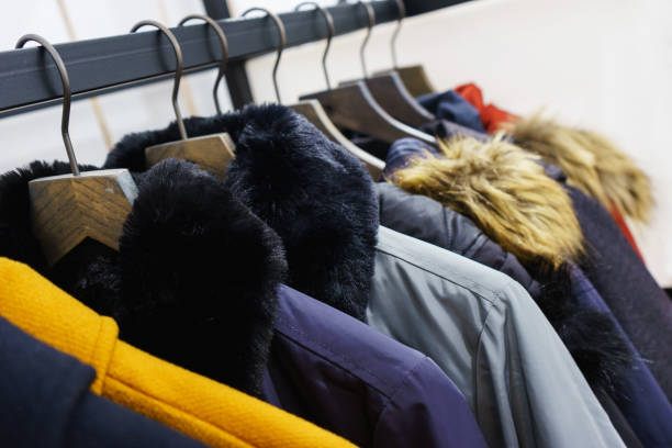 Modern outerwear in a shop on a hanger. Modern outerwear in a shop on a hanger. Jackets, parks and warm outerwear of different colors and denim for youth. Outerwear of different styles on the hanger in the showroom. Soft focus. winter coat stock pictures, royalty-free photos & images