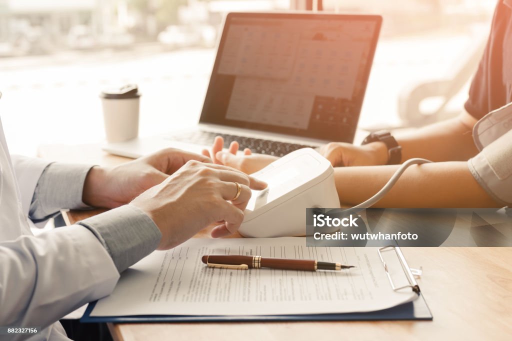 Doctor pressing pressure blood gauge button and talking to patient. Low Stock Photo