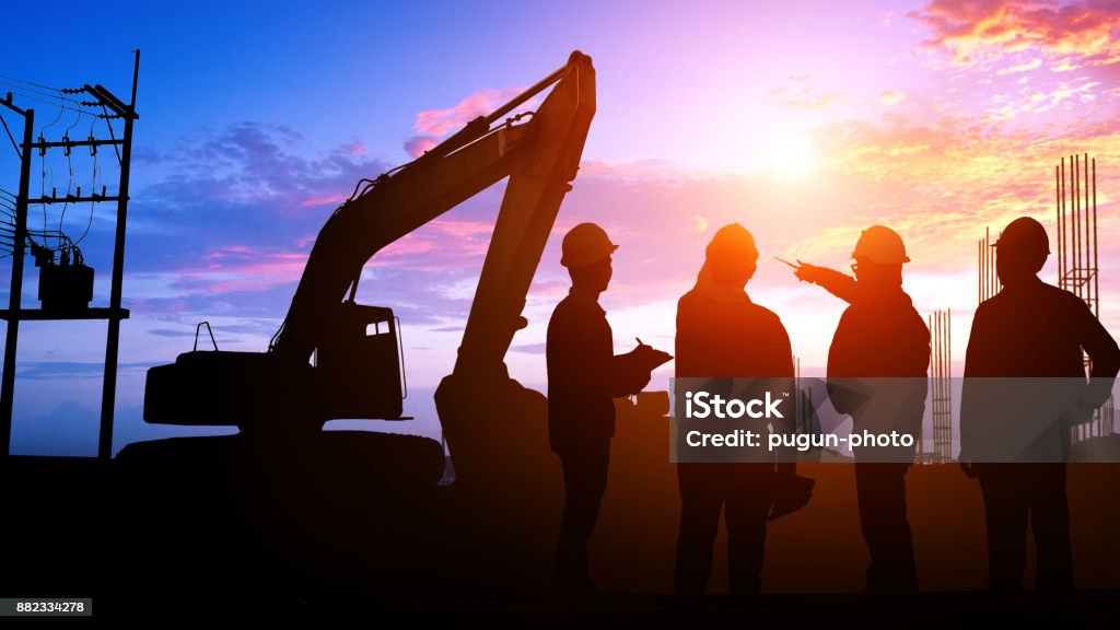 Silhouette Teams engineer Silhouette Teams engineer looking construction worker in a building site at sunset Construction Industry Stock Photo