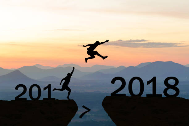 istock Happy New Year 2018 Men jump over silhouette 882346402