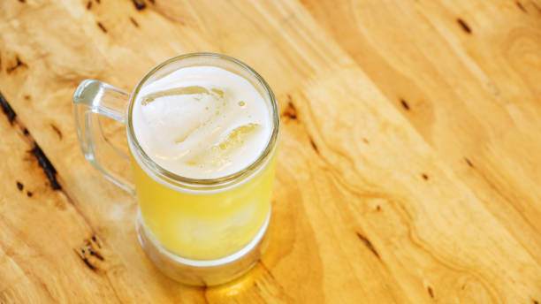 A glass of beer on a wooden table.